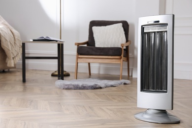 Modern electric heater on floor at home. Space for text