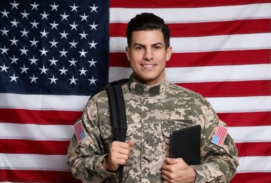 Photo of Cadet with backpack and tablet against American flag. Military education