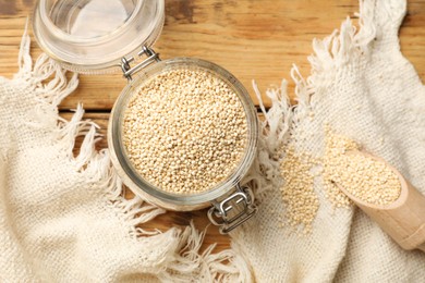 Photo of Dry quinoa seeds and scoop in glass jar on wooden table, top view