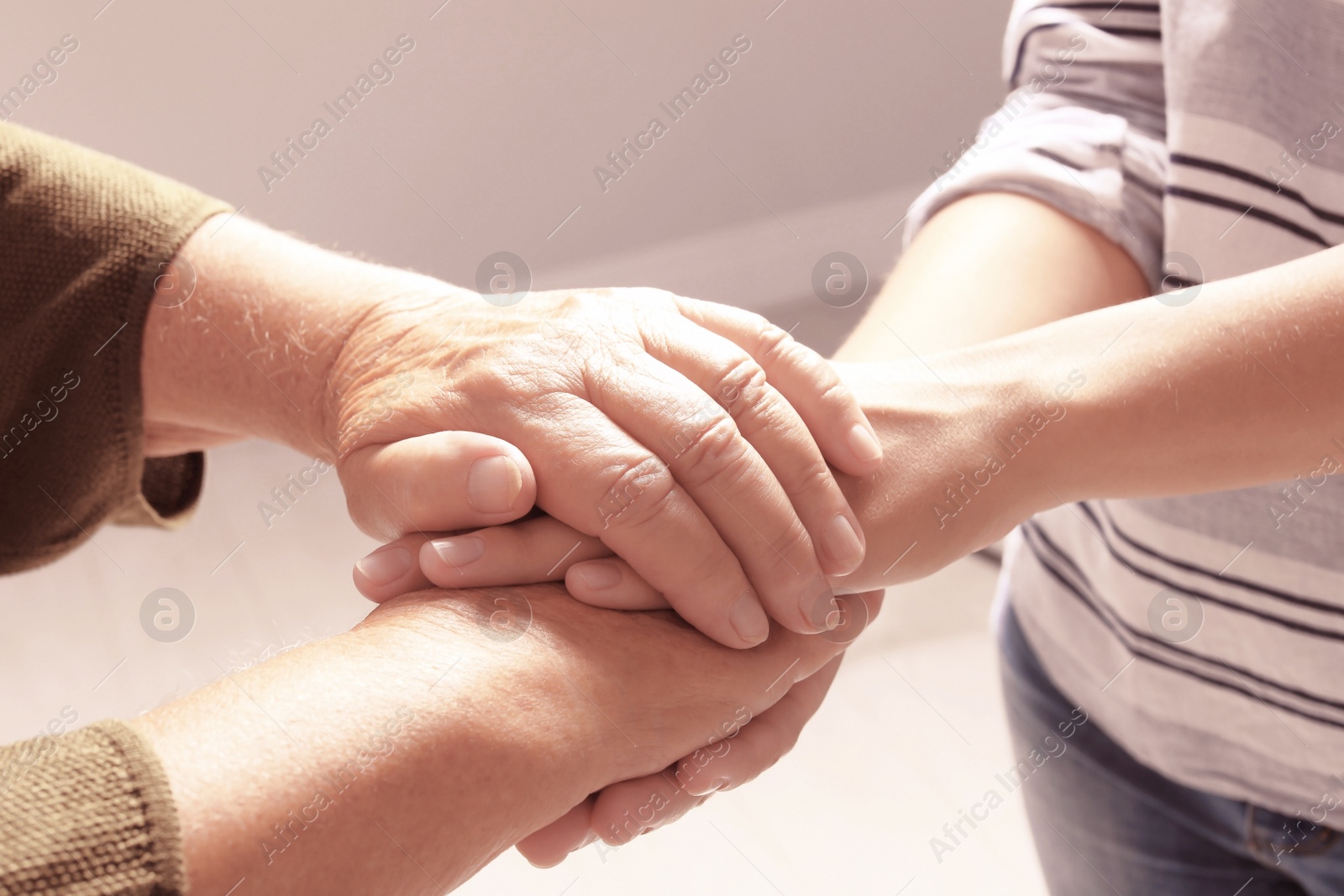 Photo of Helping hands on grey background, closeup. Elderly care concept