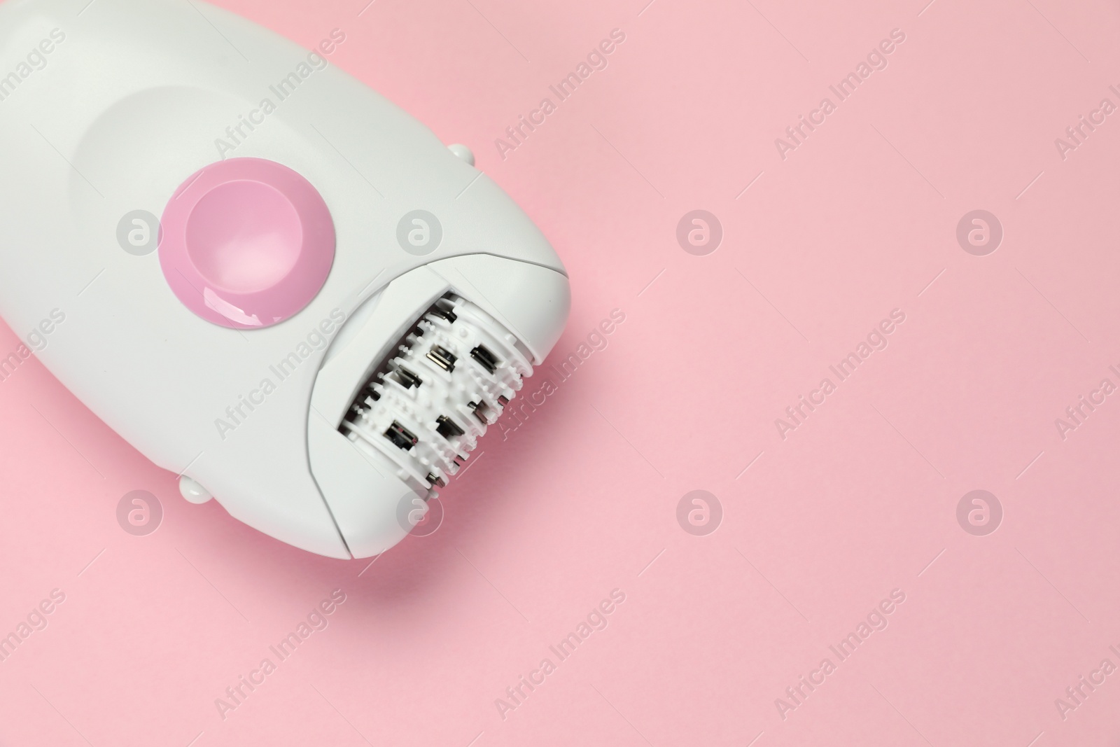 Photo of Modern epilator on pink background, top view. Space for text