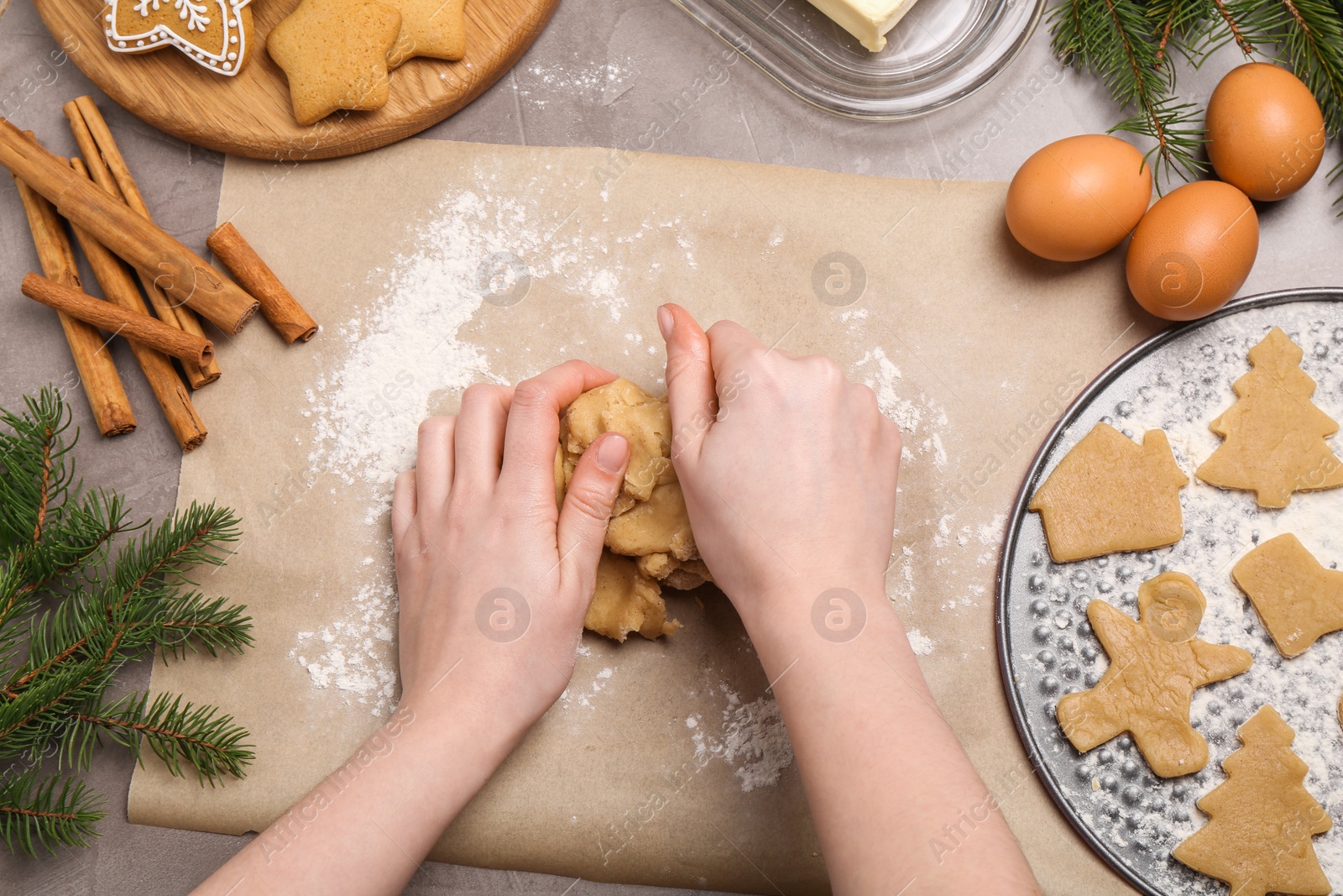 Photo of Making Christmas cookies. Woman kneading dough at grey table, top view