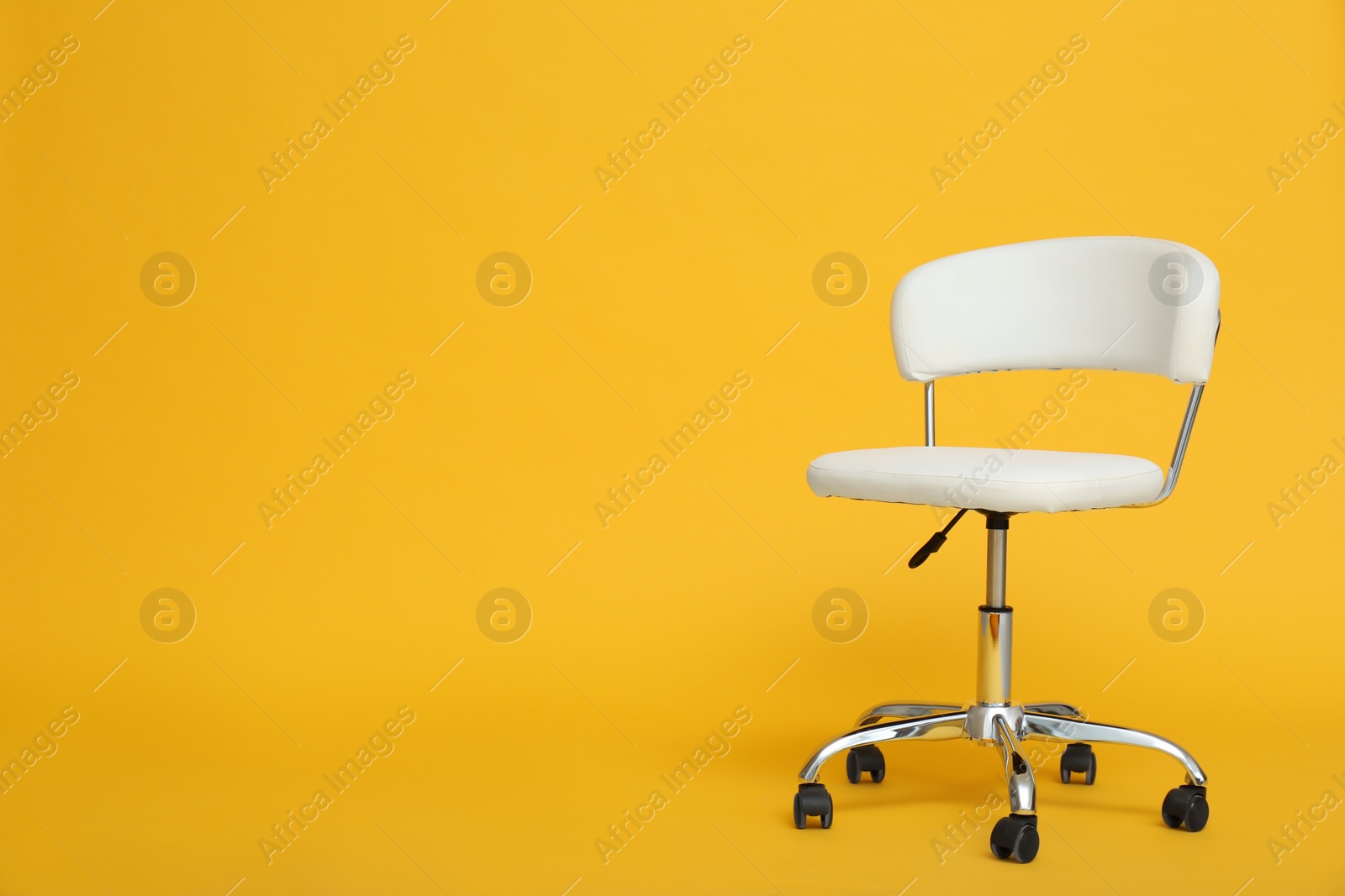 Photo of Modern office chair on yellow background. Space for text