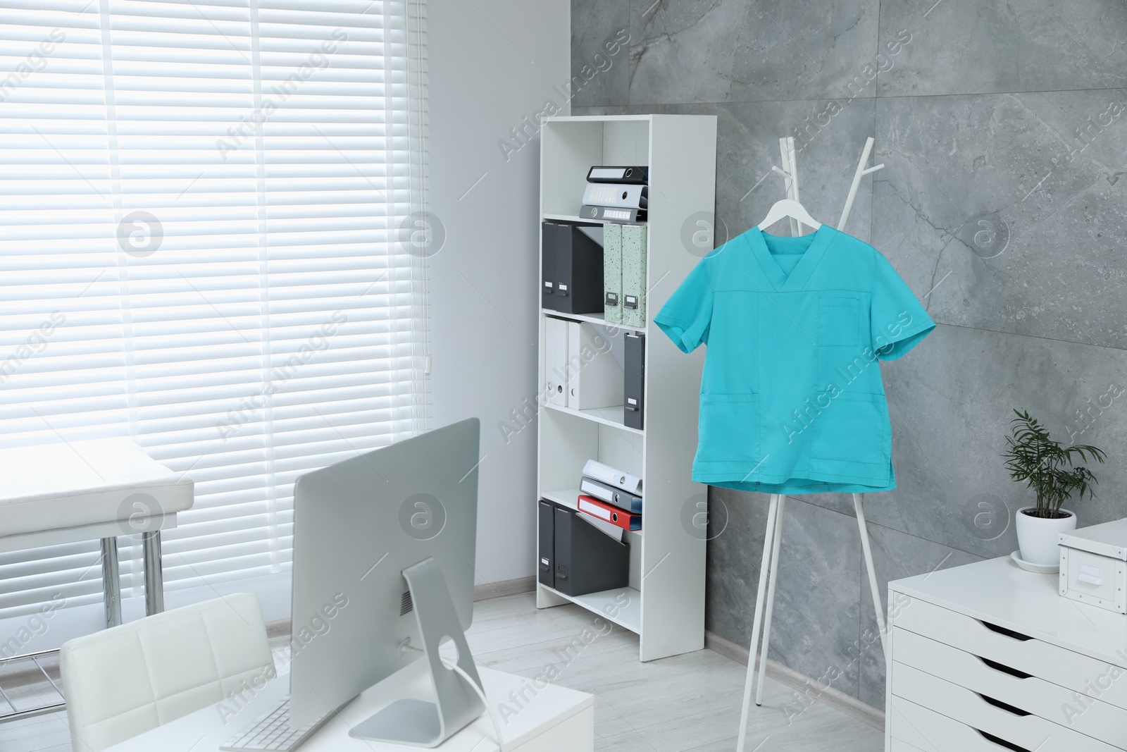 Photo of Turquoise medical uniform hanging on rack in clinic