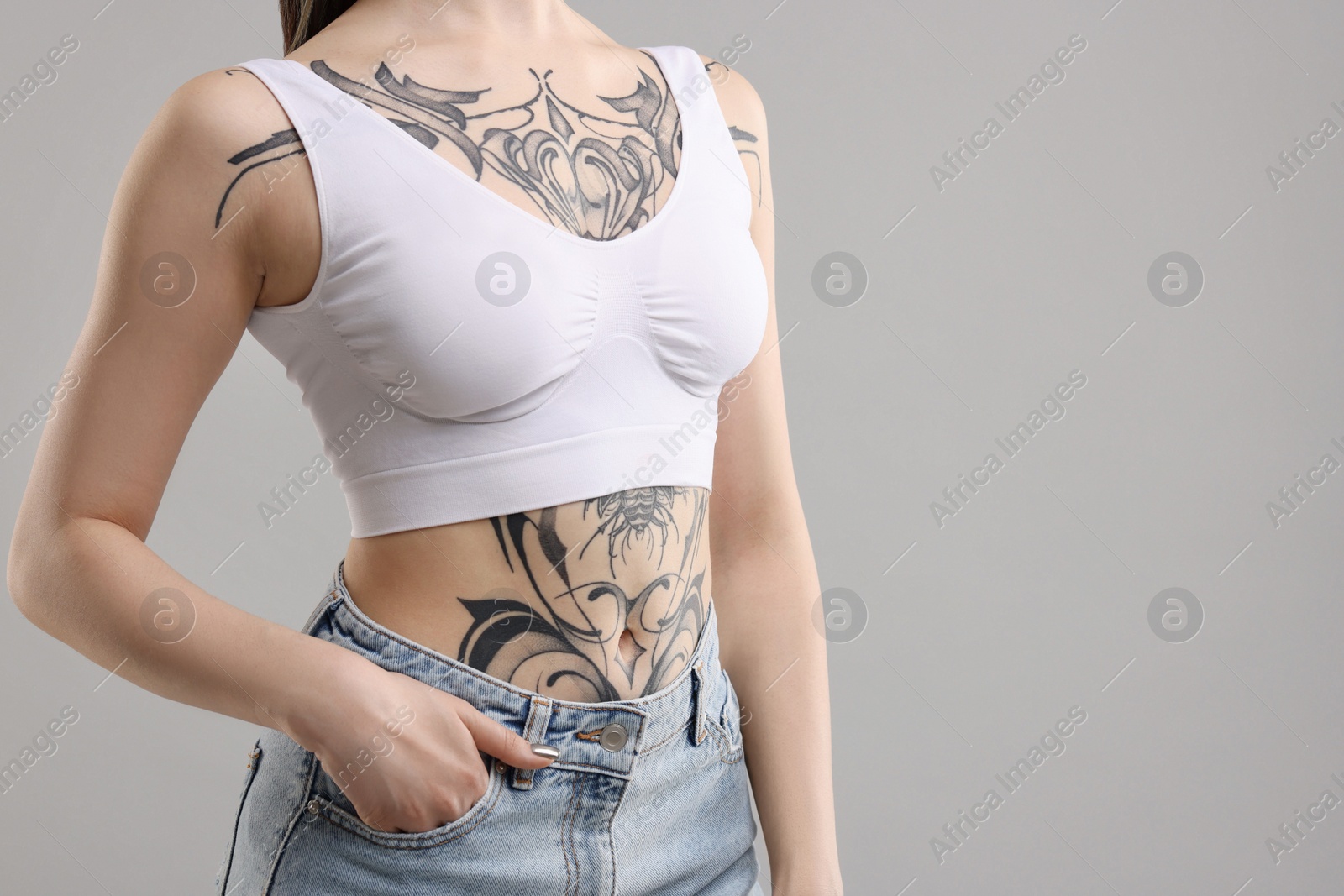 Photo of Woman with cool tattoos on grey background, closeup. Space for text