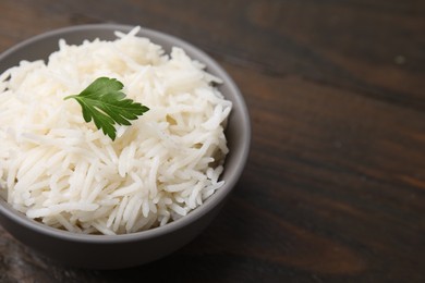 Photo of Bowl of delicious rice with parsley on table, closeup. Space for text