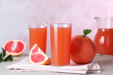 Photo of Tasty freshly made grapefruit juice and fruits on white wooden table