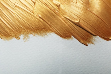 Photo of Golden paint brush strokes on white background. Space for text