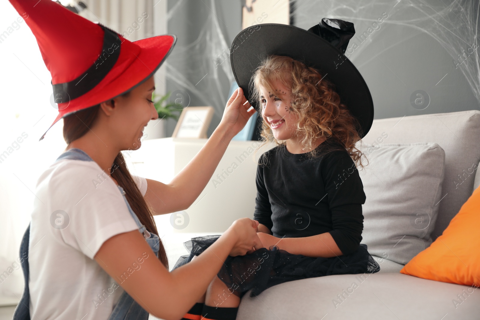 Photo of Mother and cute little girl wearing Halloween costumes at home
