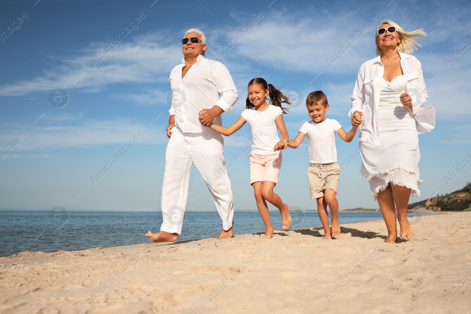 Photo of Cute little children with grandparents spending time together on sea beach