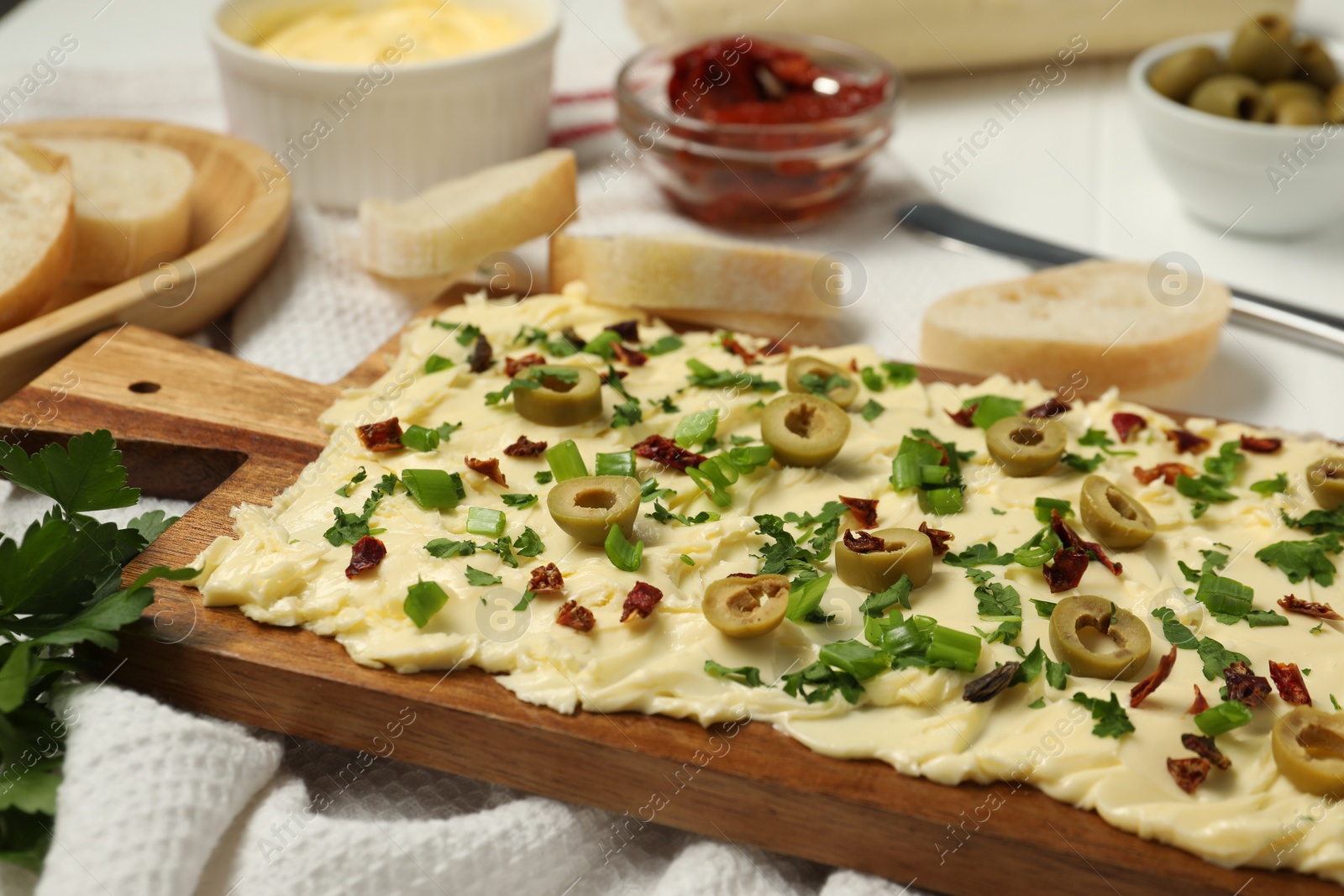 Photo of Fresh butter board with cut olives, onion and sun-dried tomatoes on table