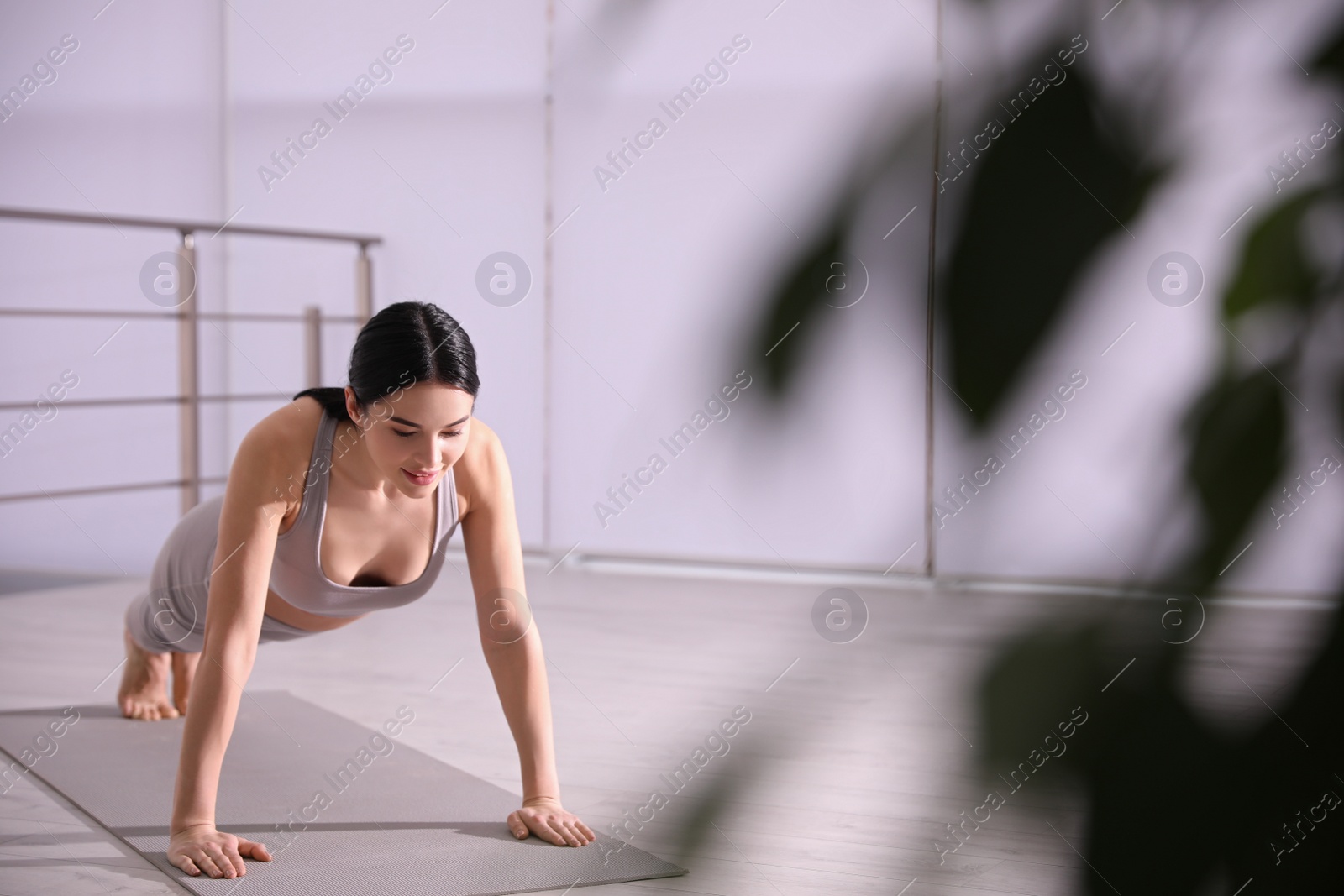 Photo of Young woman practicing plank asana in yoga studio. Phalankasana pose