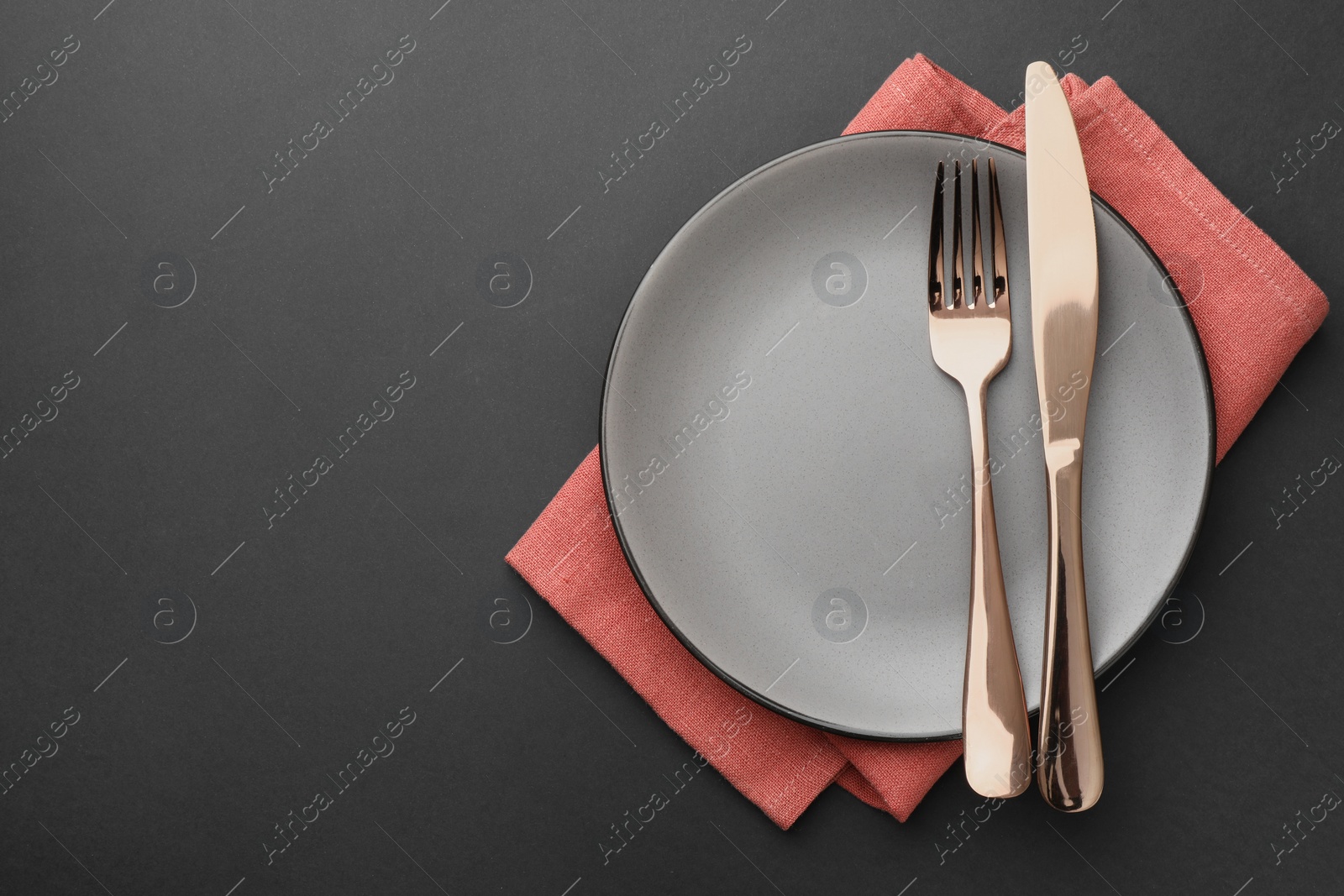 Photo of Clean plate, cutlery and napkin on grey table, top view. Space for text