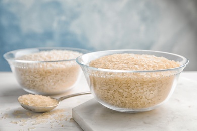 Photo of Bowl with uncooked rice on kitchen table