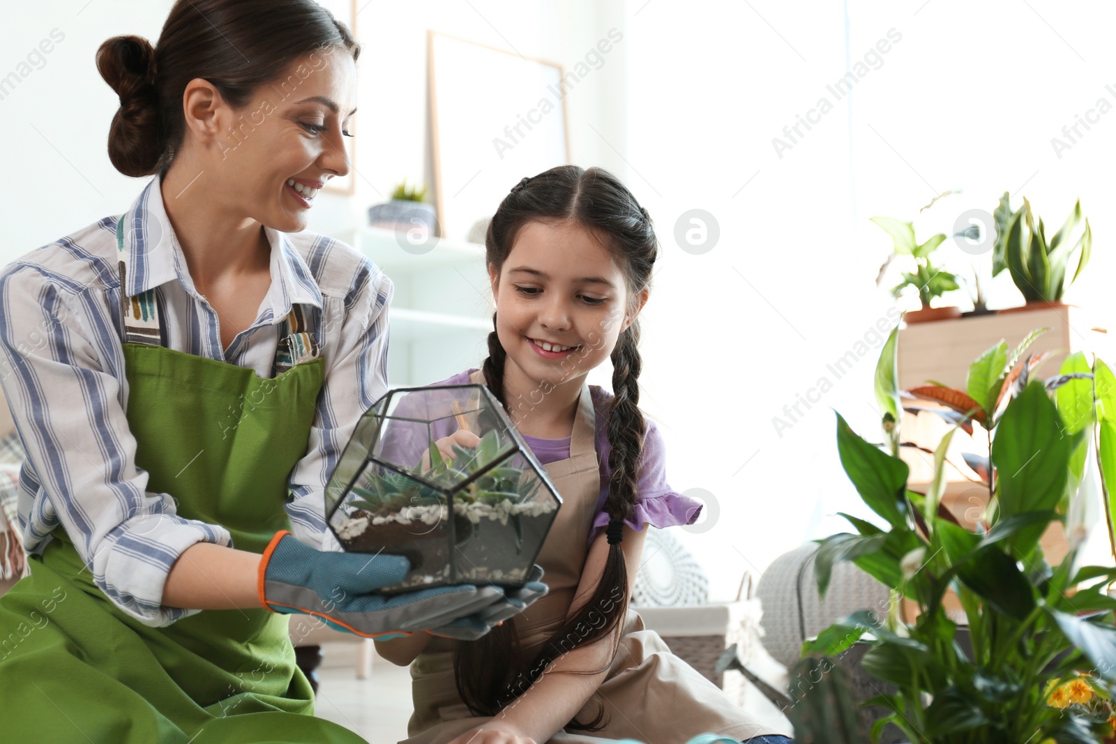 Photo of Mother and daughter taking care of plants at home