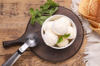 Photo of Bowl of ice cream and mint leaves on wooden table, flat lay