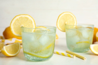 Photo of Soda water with lemon slices and ice cubes on white table. Space for text