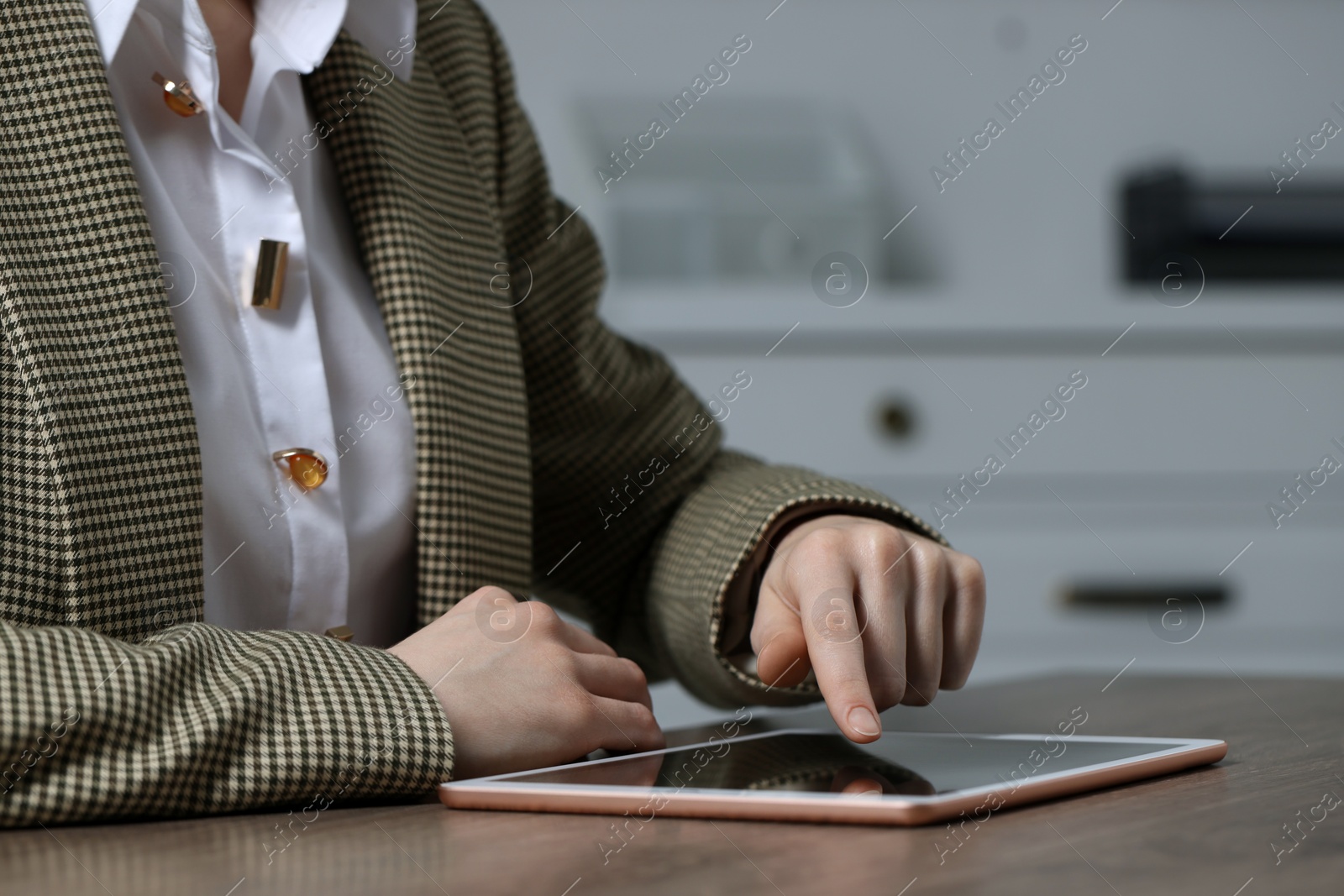 Photo of Closeup view of woman using modern tablet at table on blurred background