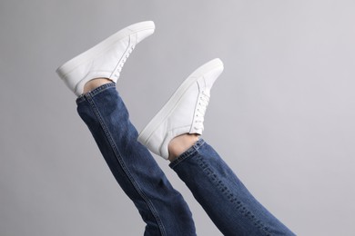 Photo of Man wearing stylish white sneakers on grey background, closeup