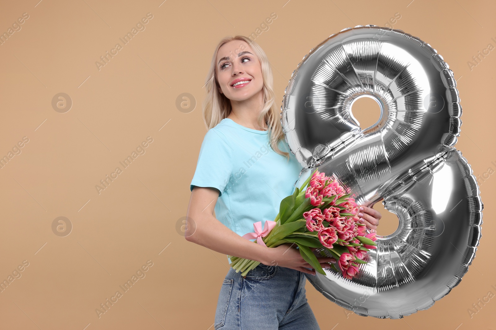 Photo of Happy Women's Day. Charming lady holding bouquet of beautiful flowers and balloon in shape of number 8 on beige background, space for text