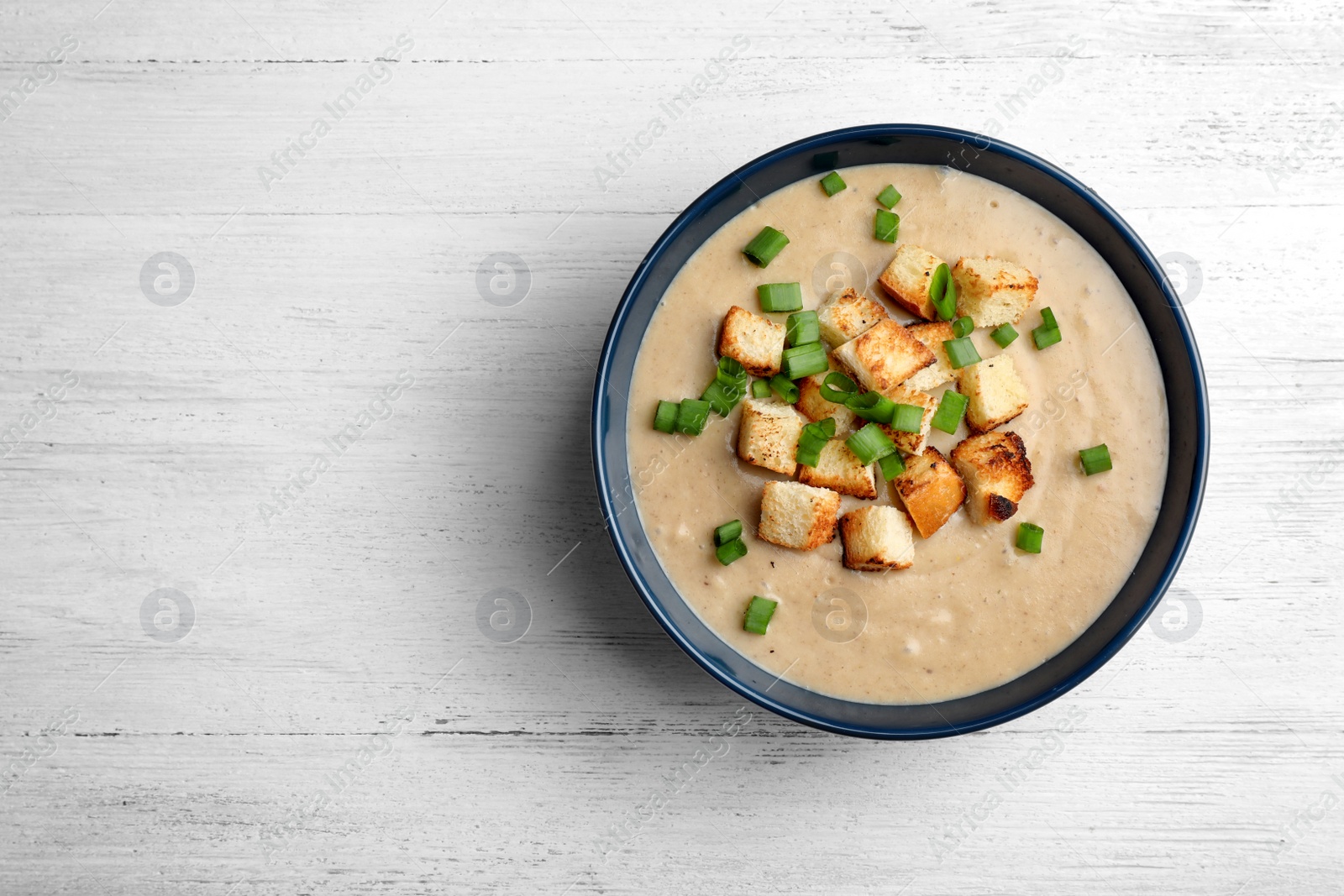 Photo of Bowl of fresh homemade mushroom soup on wooden background, top view with space for text