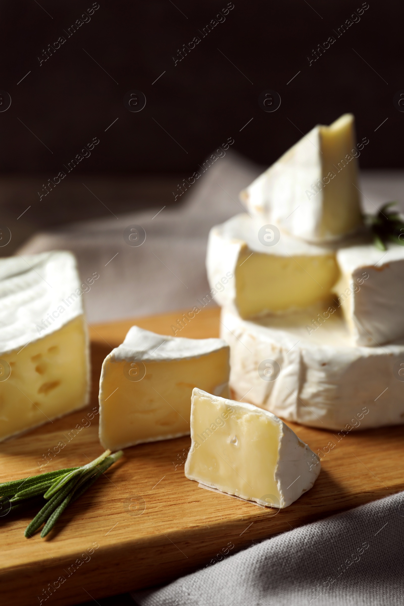 Photo of Wooden board with delicious cheeses on table