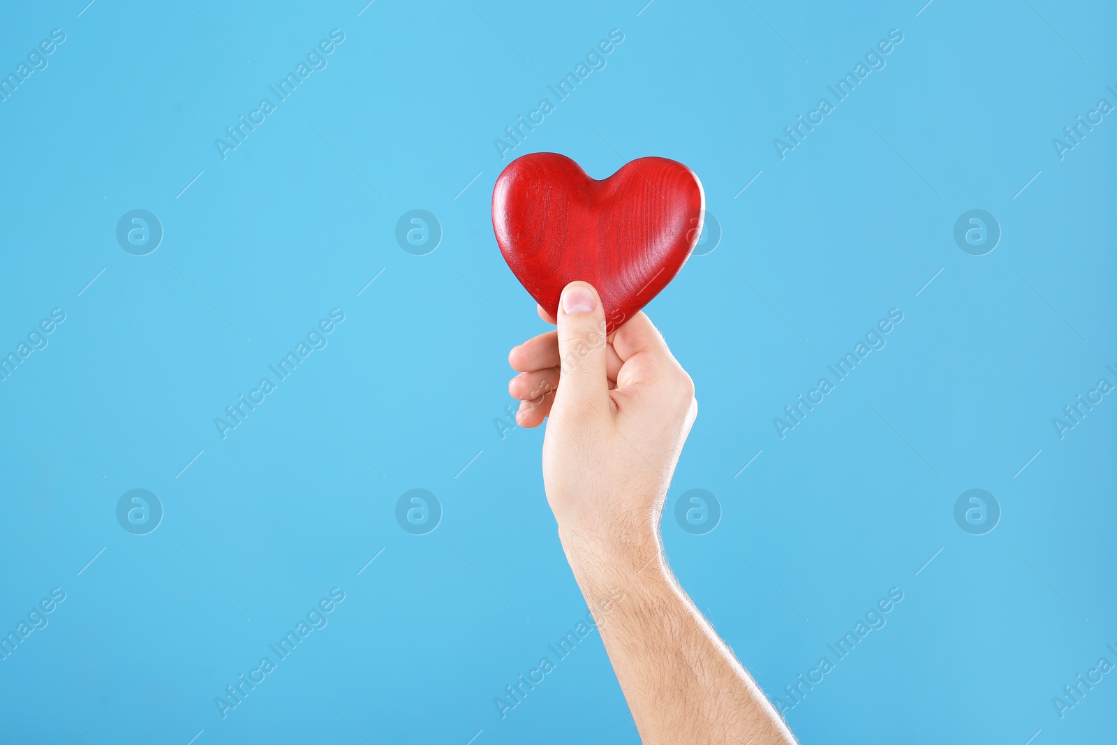 Photo of Man holding decorative heart in hand on color background