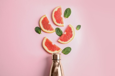 Flat lay composition with bottle, grapefruit slices and leaves on color background