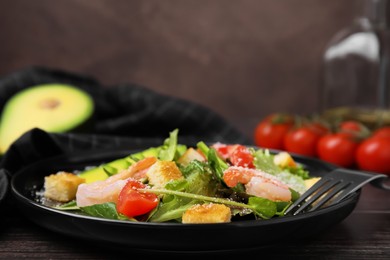 Photo of Delicious salad with croutons, avocado and shrimp served on wooden table, closeup