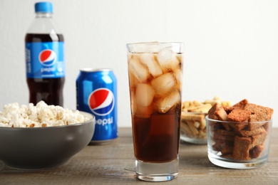 MYKOLAIV, UKRAINE - FEBRUARY 15, 2021: Glass of Pepsi and snacks on wooden table