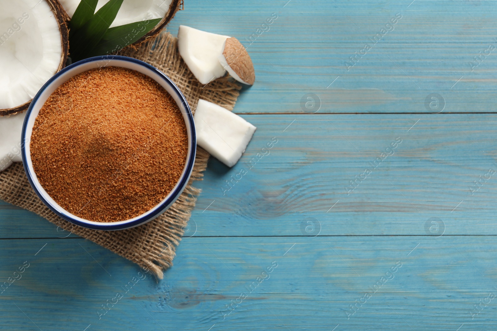 Photo of Flat lay composition with natural coconut sugar on light blue wooden table, space for text