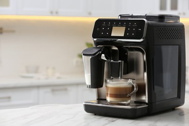 Modern coffee machine with glass cup of latte on white marble countertop in kitchen