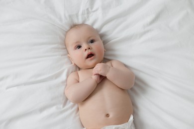 Photo of Cute little baby lying on white bed, top view