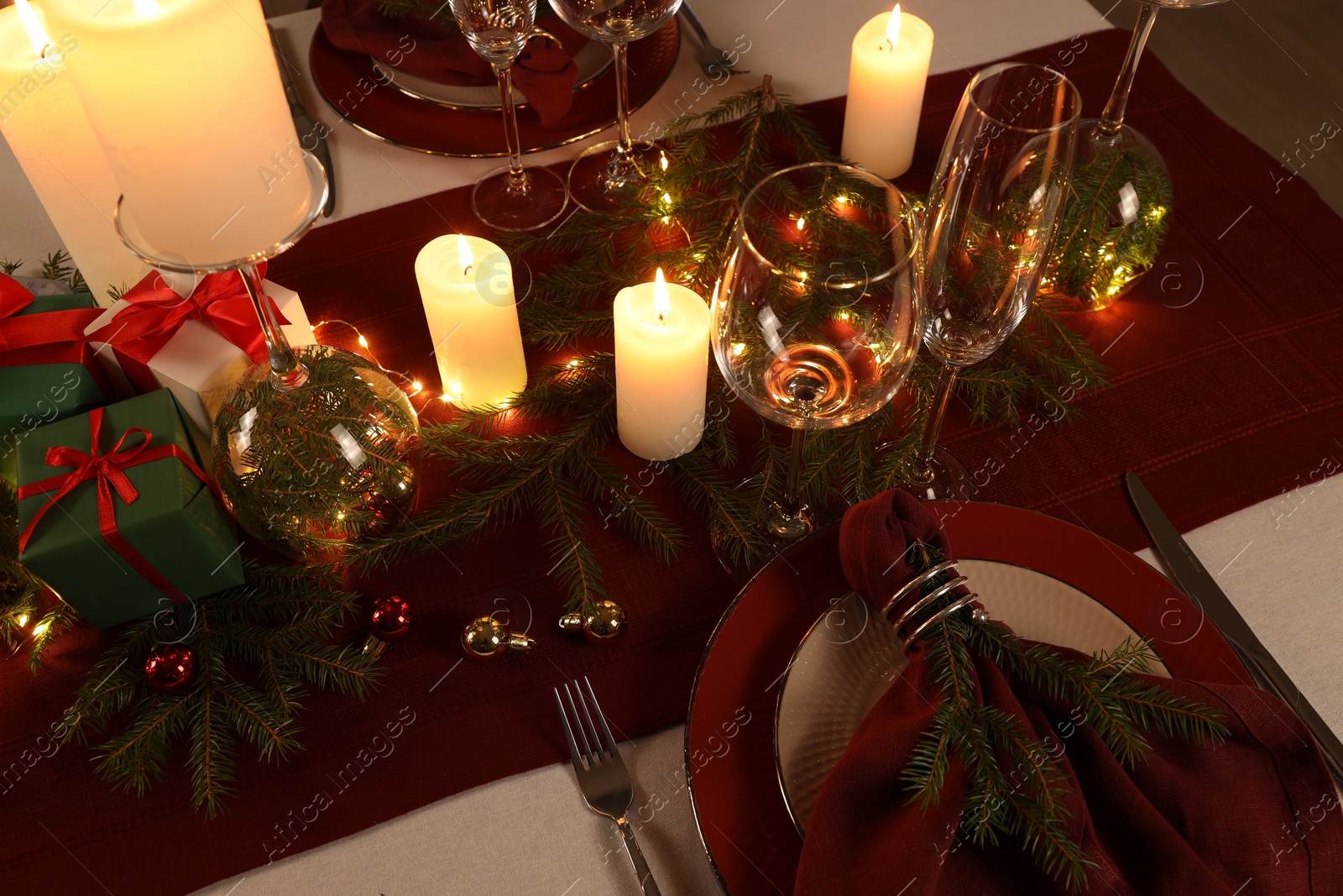 Photo of Christmas table setting with burning candles and festive decor, above view