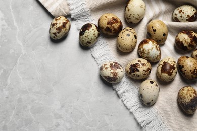 Photo of Many speckled quail eggs on light grey marble table, flat lay. Space for text