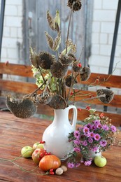 Beautiful autumn composition with different flowers on wooden table outdoors