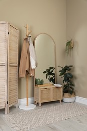 Photo of Stylish hallway room interior with wooden commode, coat rack and large mirror