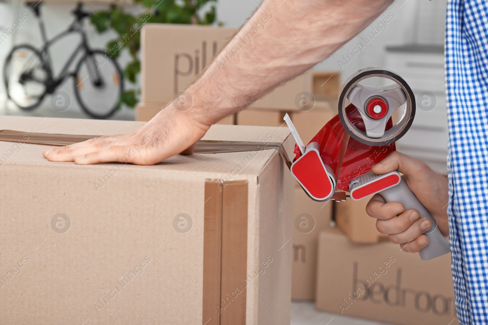 Photo of Man packing cardboard box indoors, closeup. Moving day