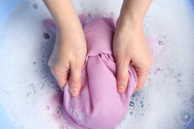 Photo of Top view of woman hand washing color clothing in suds, closeup