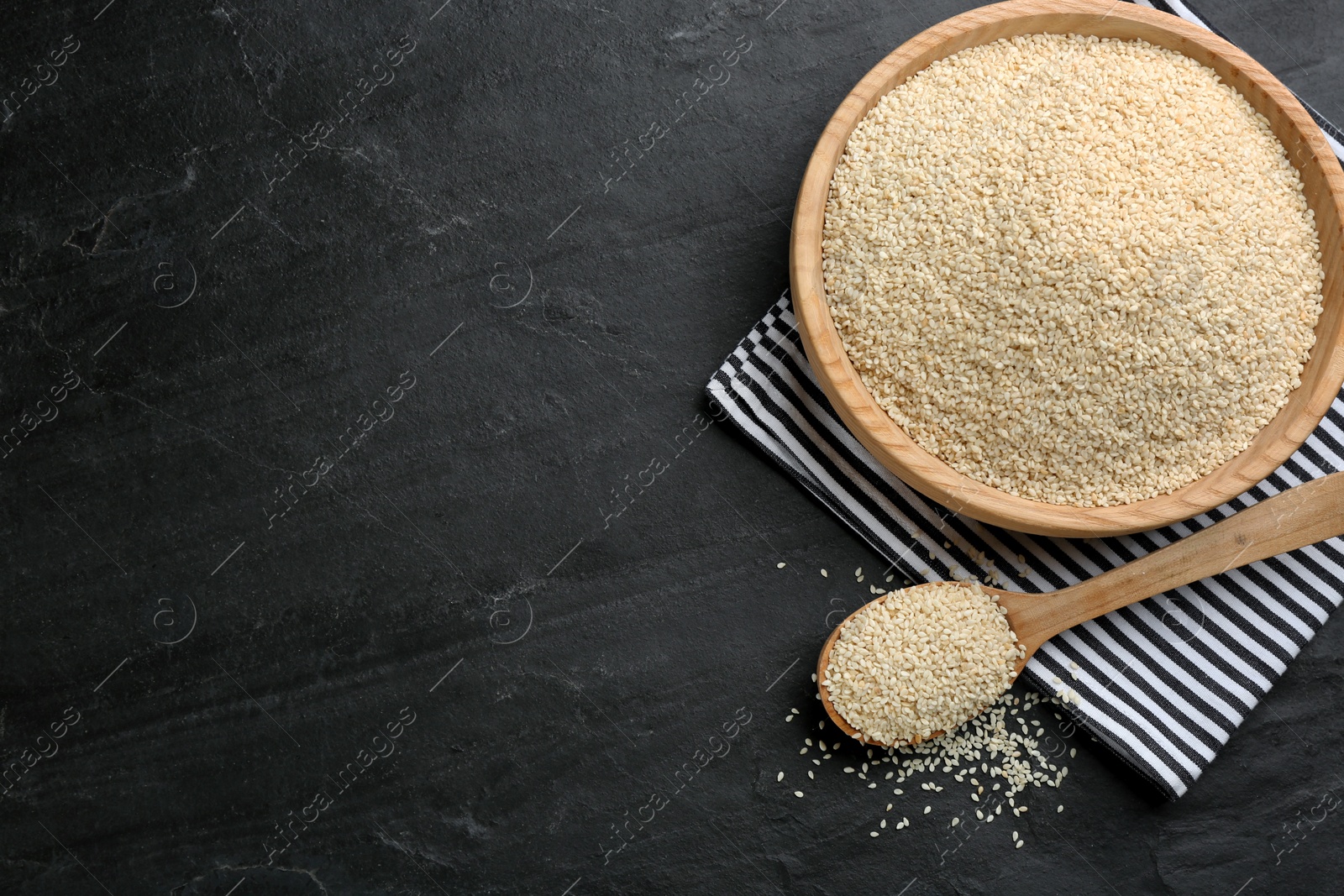Photo of White sesame seeds on black table, flat lay. Space for text