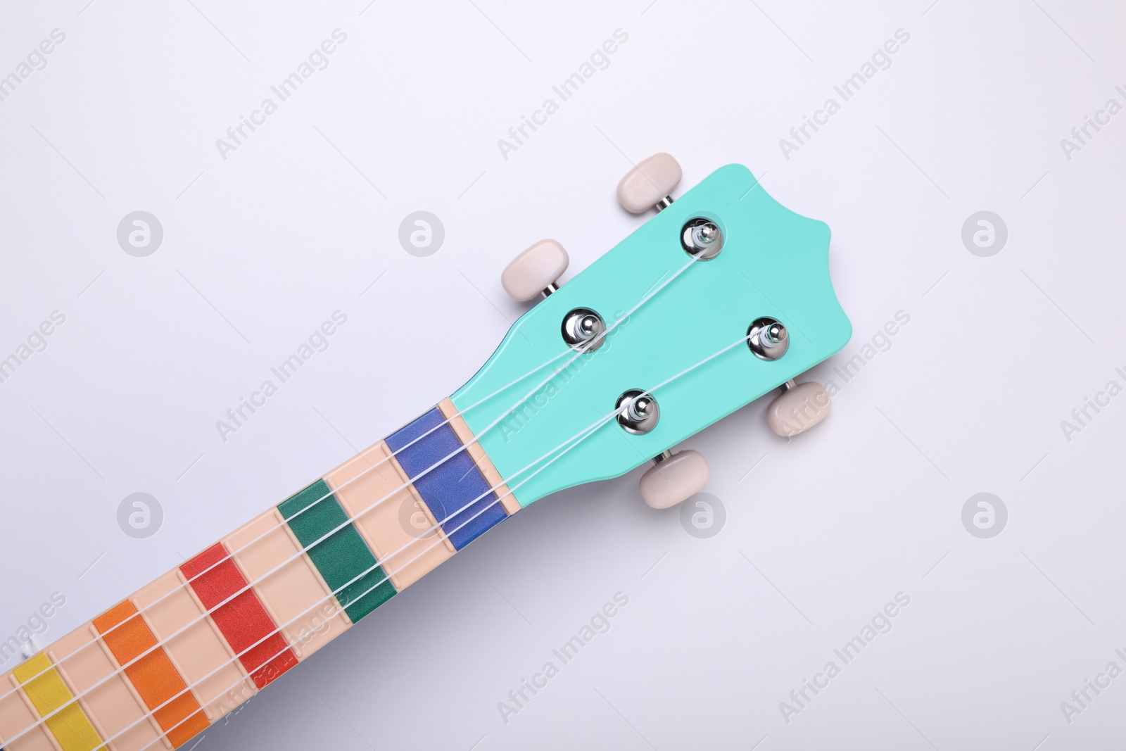 Photo of Colorful ukulele neck on white background, top view. String musical instrument