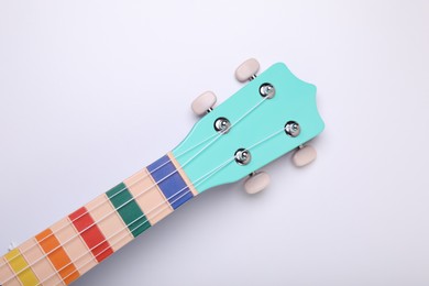 Colorful ukulele neck on white background, top view. String musical instrument