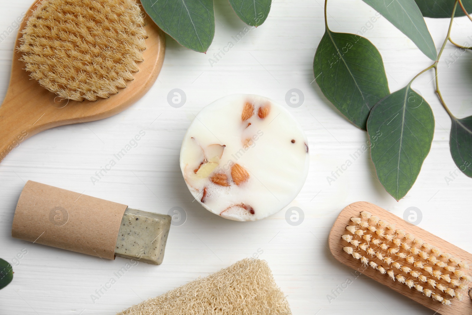 Photo of Eco friendly personal care products and leaves on white wooden table, flat lay