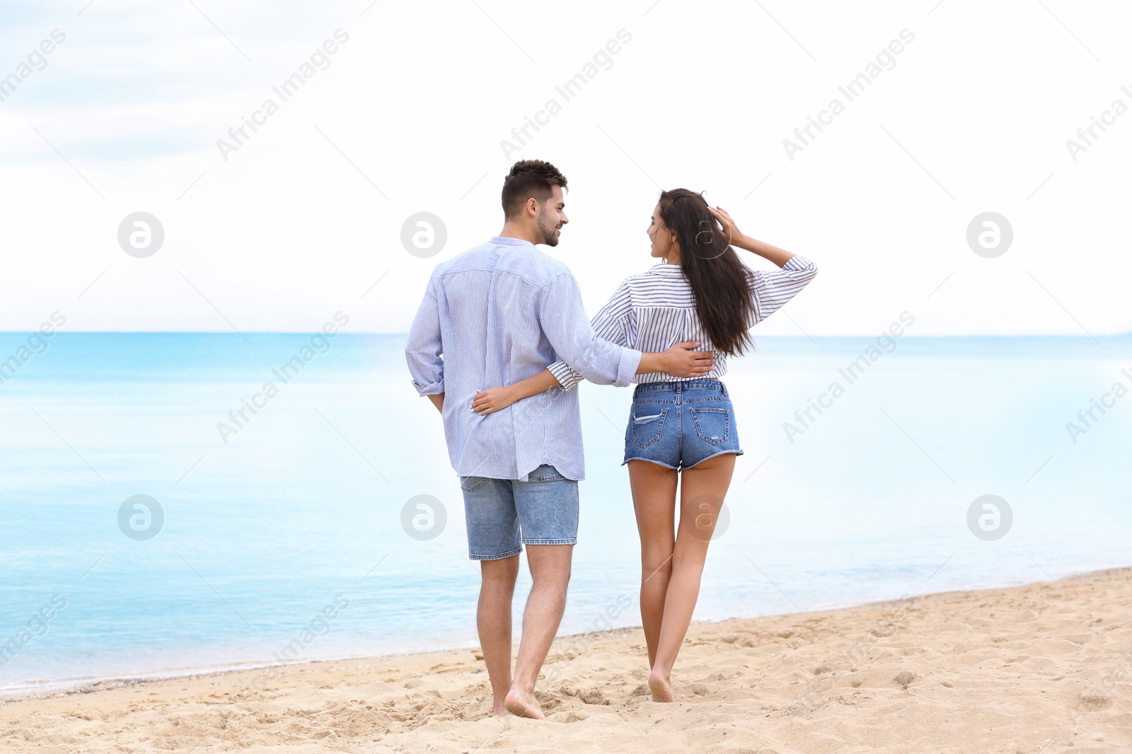 Photo of Happy young couple walking together on beach near sea