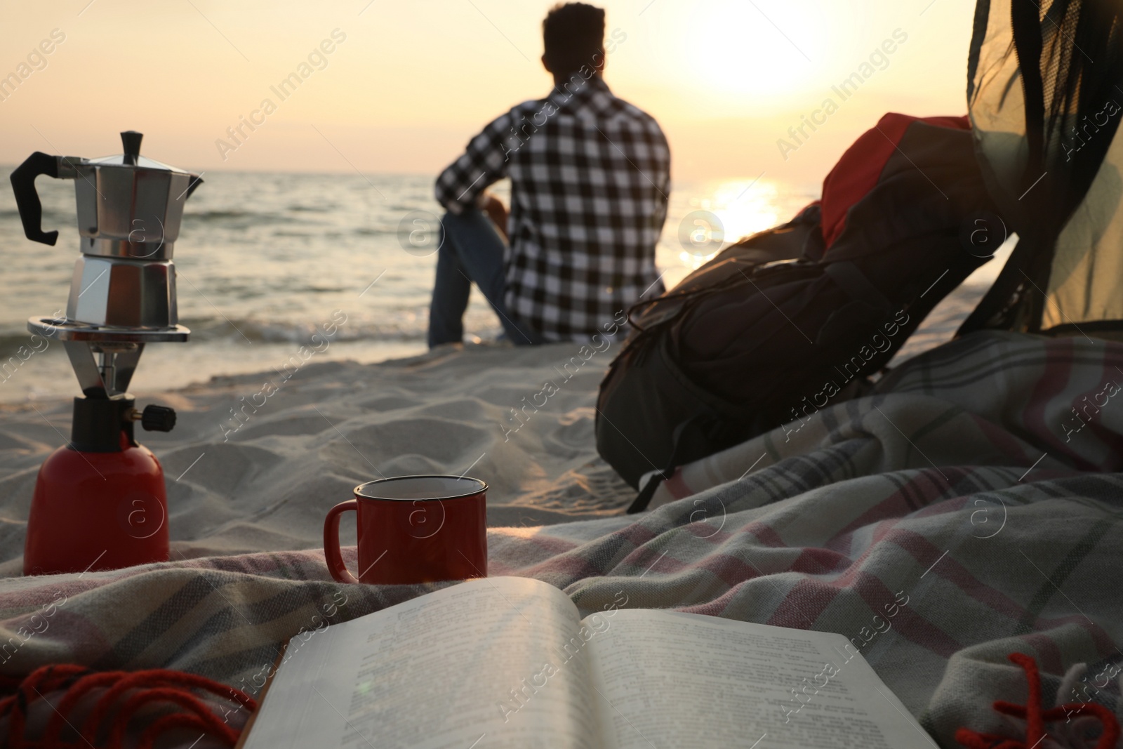 Photo of Man enjoying sunset on beach, view from camping tent