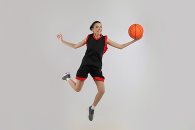 Professional sportswoman playing basketball on grey background