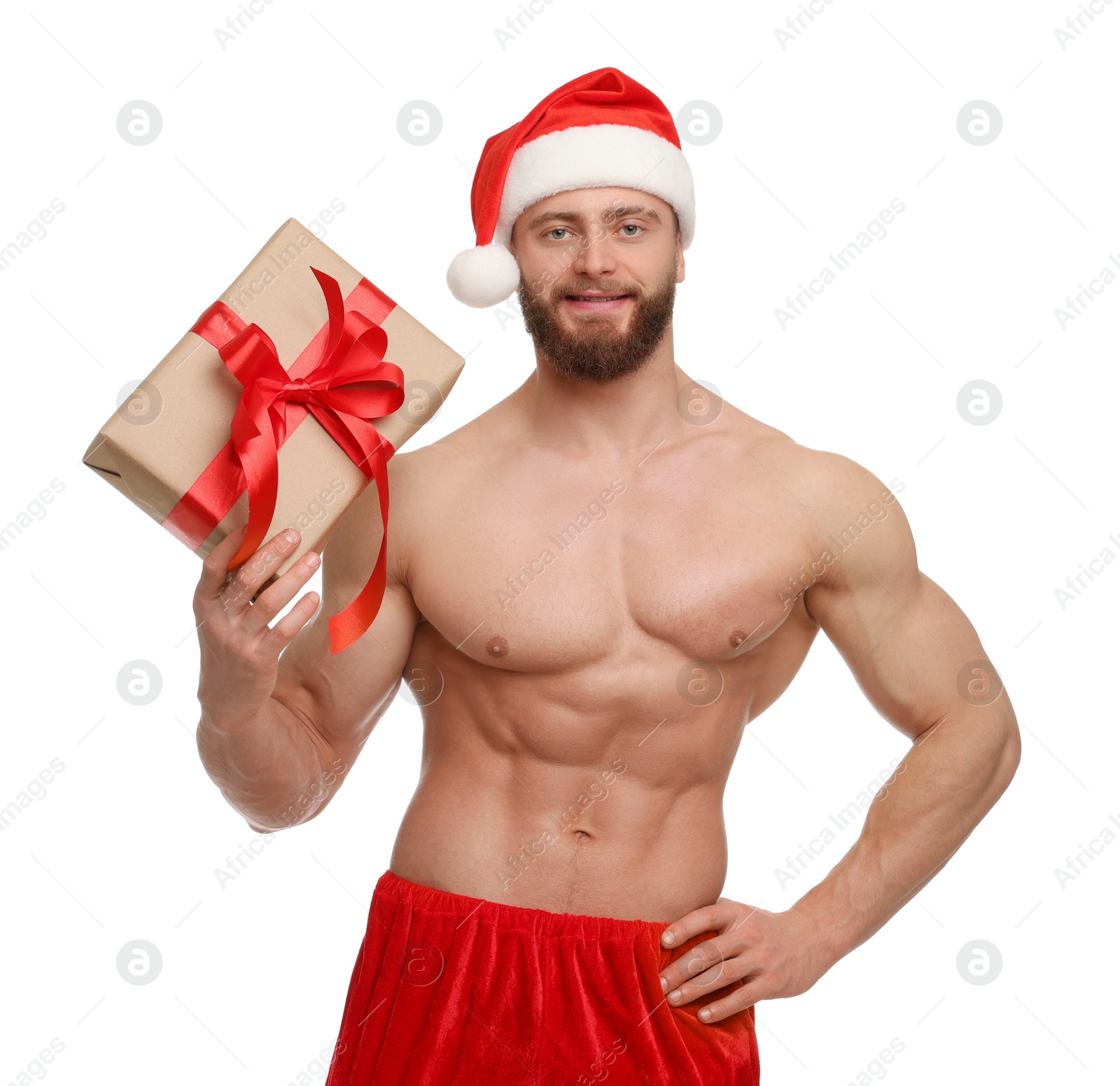 Photo of Attractive young man with muscular body in Santa hat holding Christmas gift box on white background