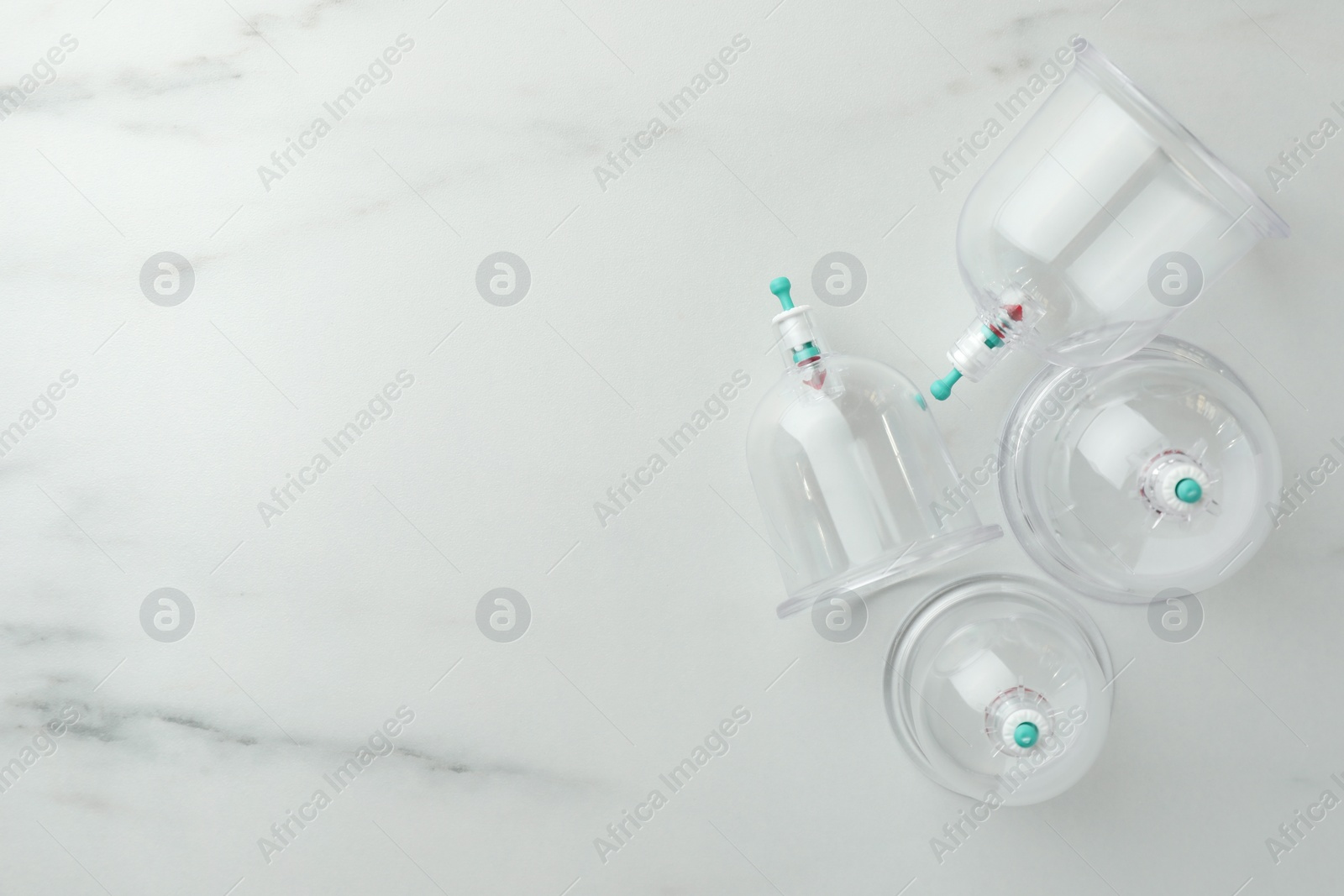 Photo of Plastic cups on white marble table, flat lay with space for text. Cupping therapy