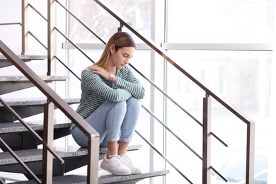 Photo of Emotional teenage girl sitting on stairs indoors