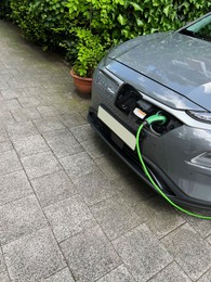 Charging modern electric car outdoors on spring day